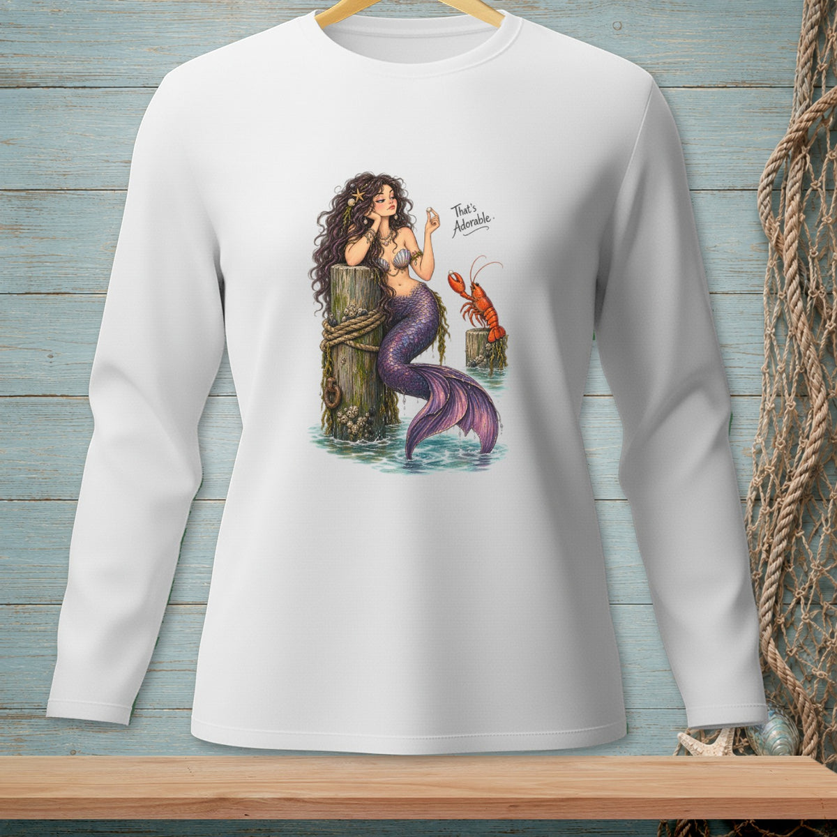 Mermaid with purple tail sits on a wooden post with a lobster and text "That's Adorable."