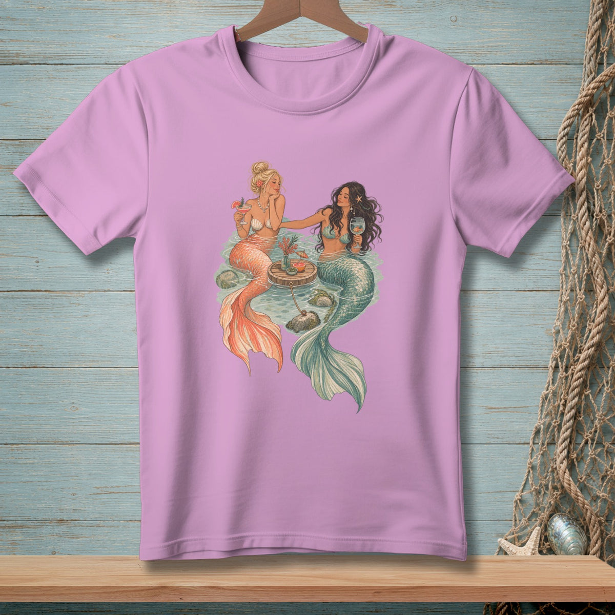 Two mermaids with drinks sit on a raft in the water.