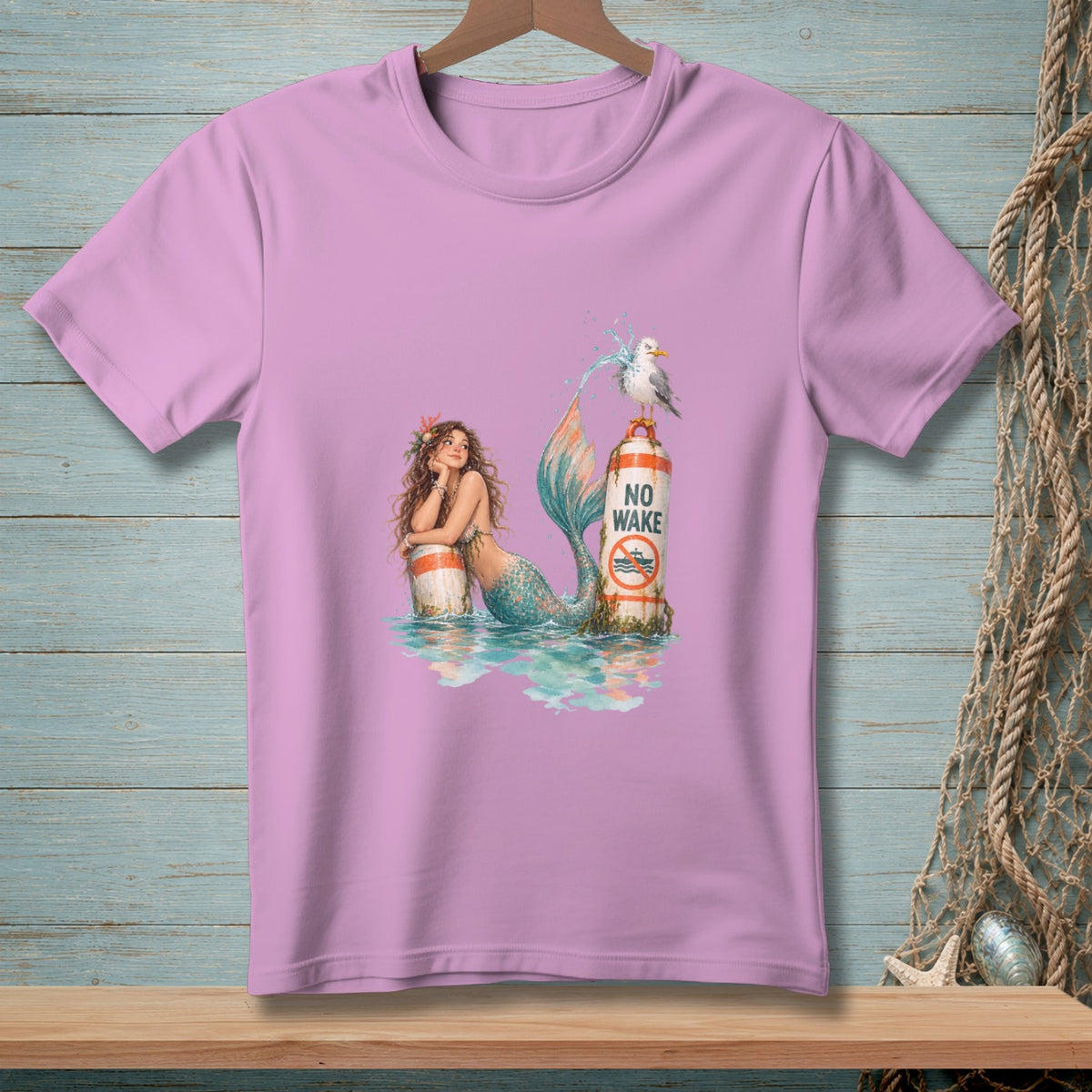 Pink t-shirt with mermaid and seagull graphic featuring "No Wake" text.