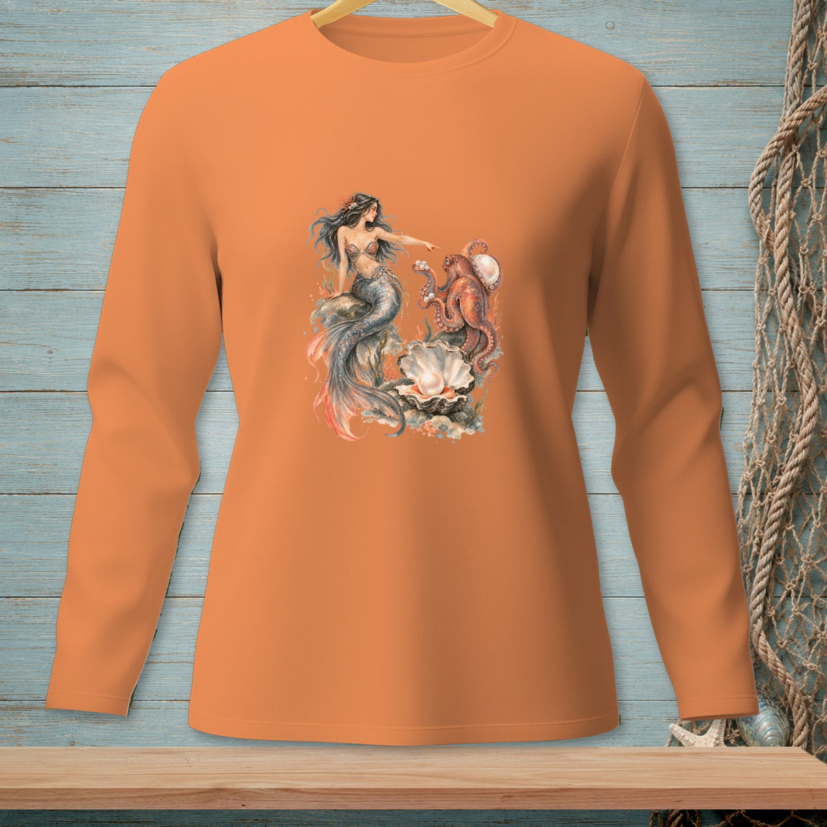 Orange long-sleeve shirt with a graphic of a mermaid and octopus by a large pearl.