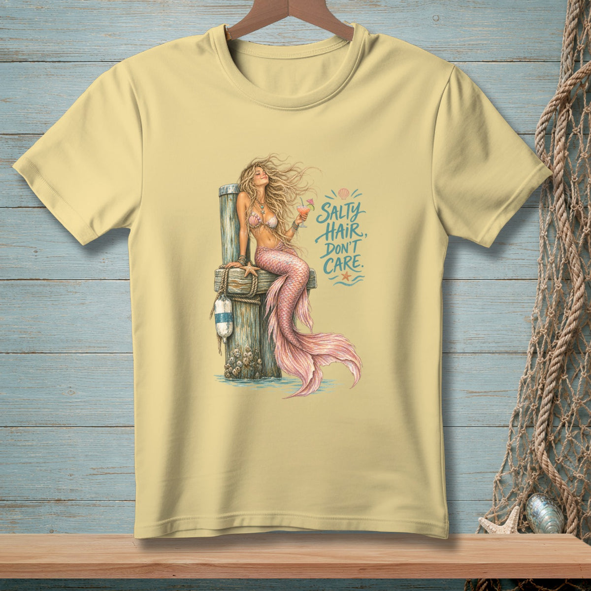 Pale yellow t-shirt with a mermaid illustration and the text "Salty Hair, Don't Care."
