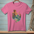 Pink t-shirt with illustration of a mermaid holding a drink near a crab.