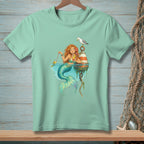 Mint green t-shirt with a mermaid fishing for a fish while holding a drink.