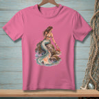 Pink t-shirt with illustration of a mermaid sitting on rocks by the sea with a crab.