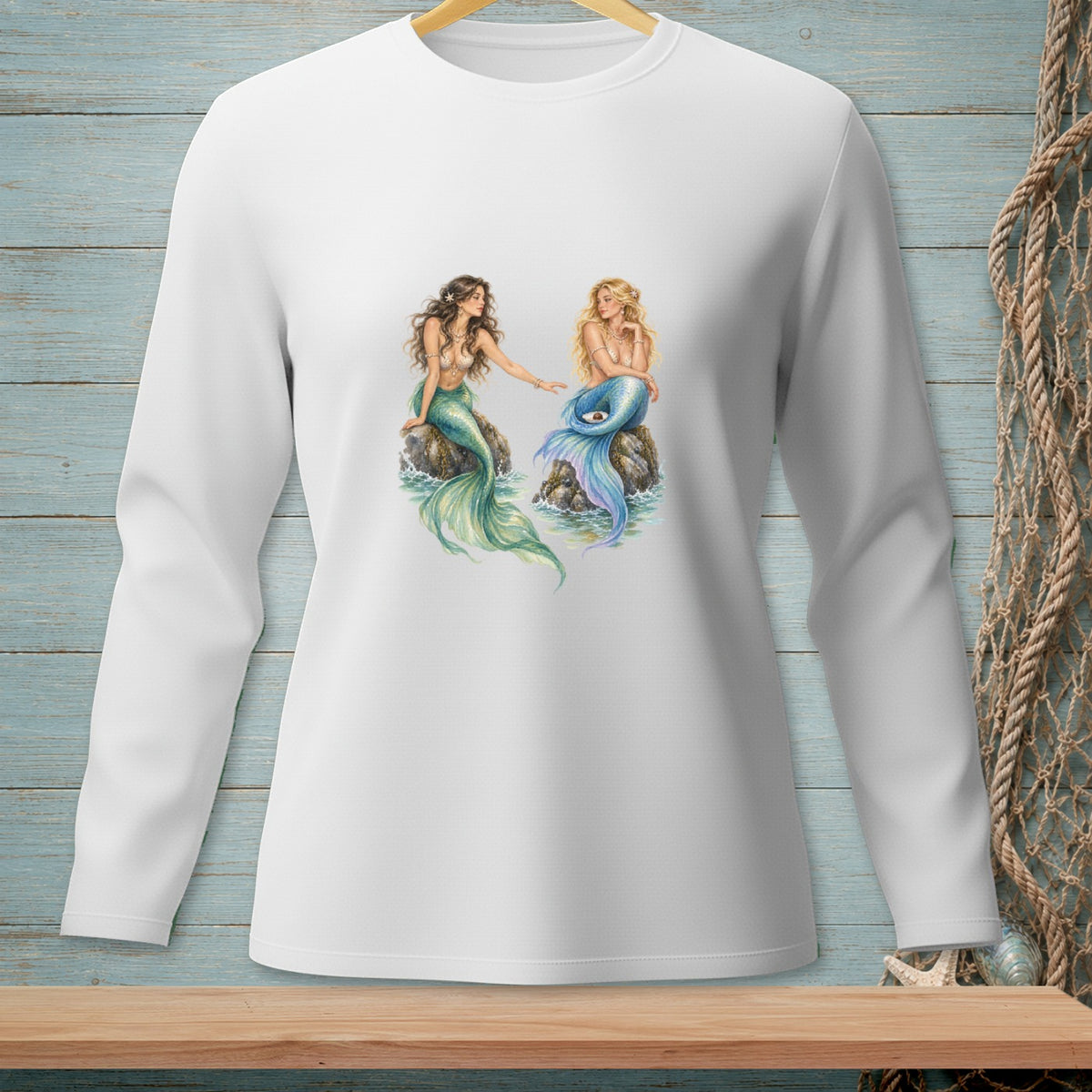 Two mermaids with green and blue tails sitting on rocks.