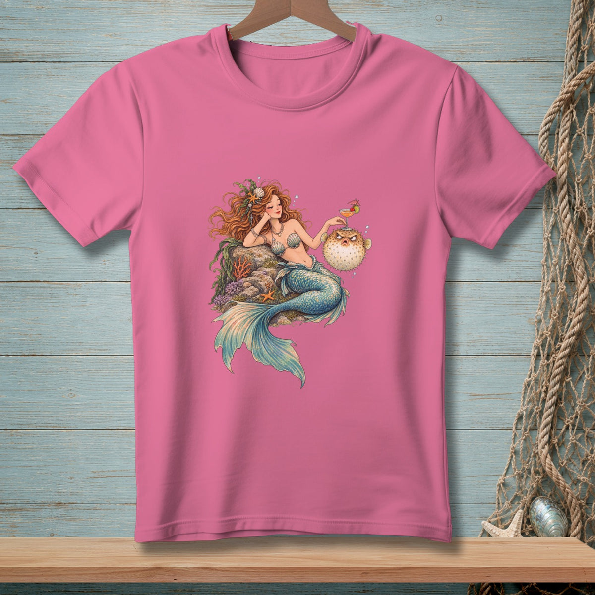 Pink t-shirt with a whimsical illustration of a mermaid and a pufferfish.