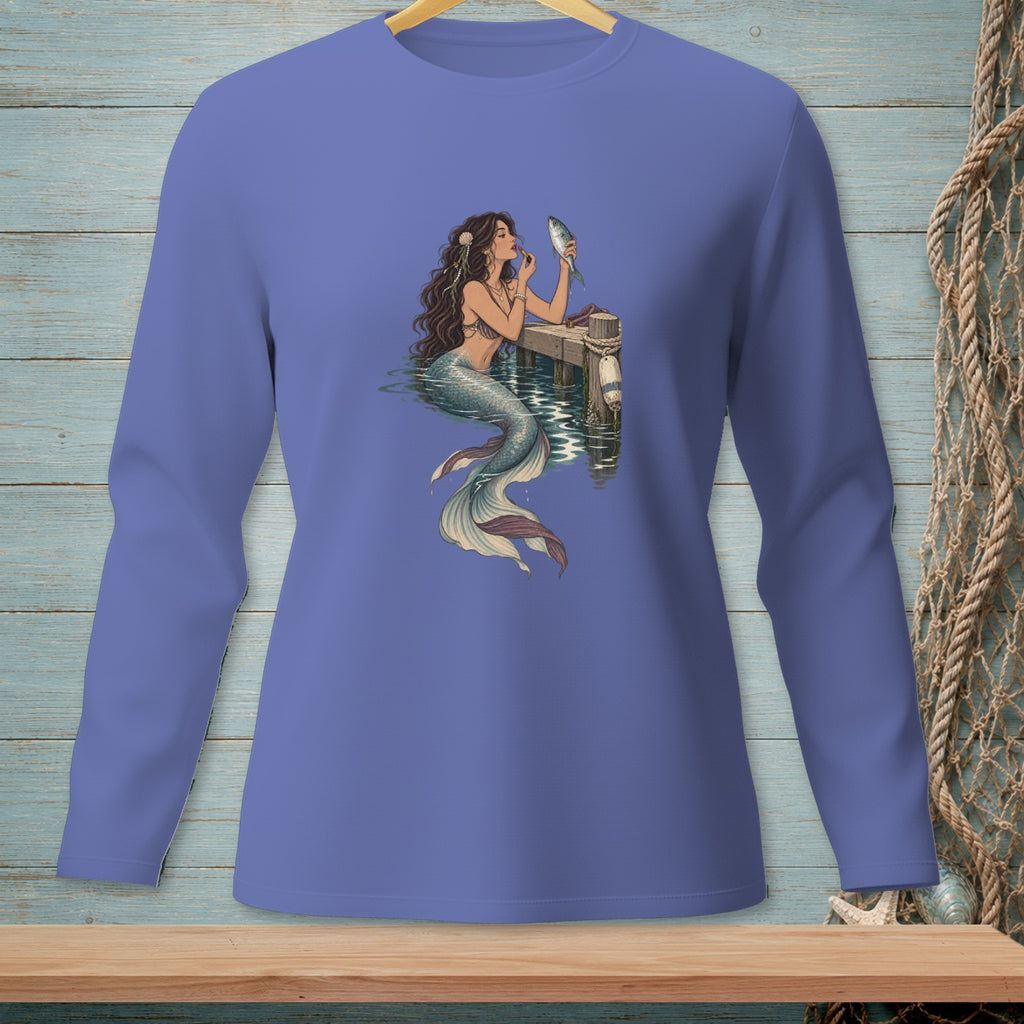 Mermaid applying makeup to a fish on a dock.