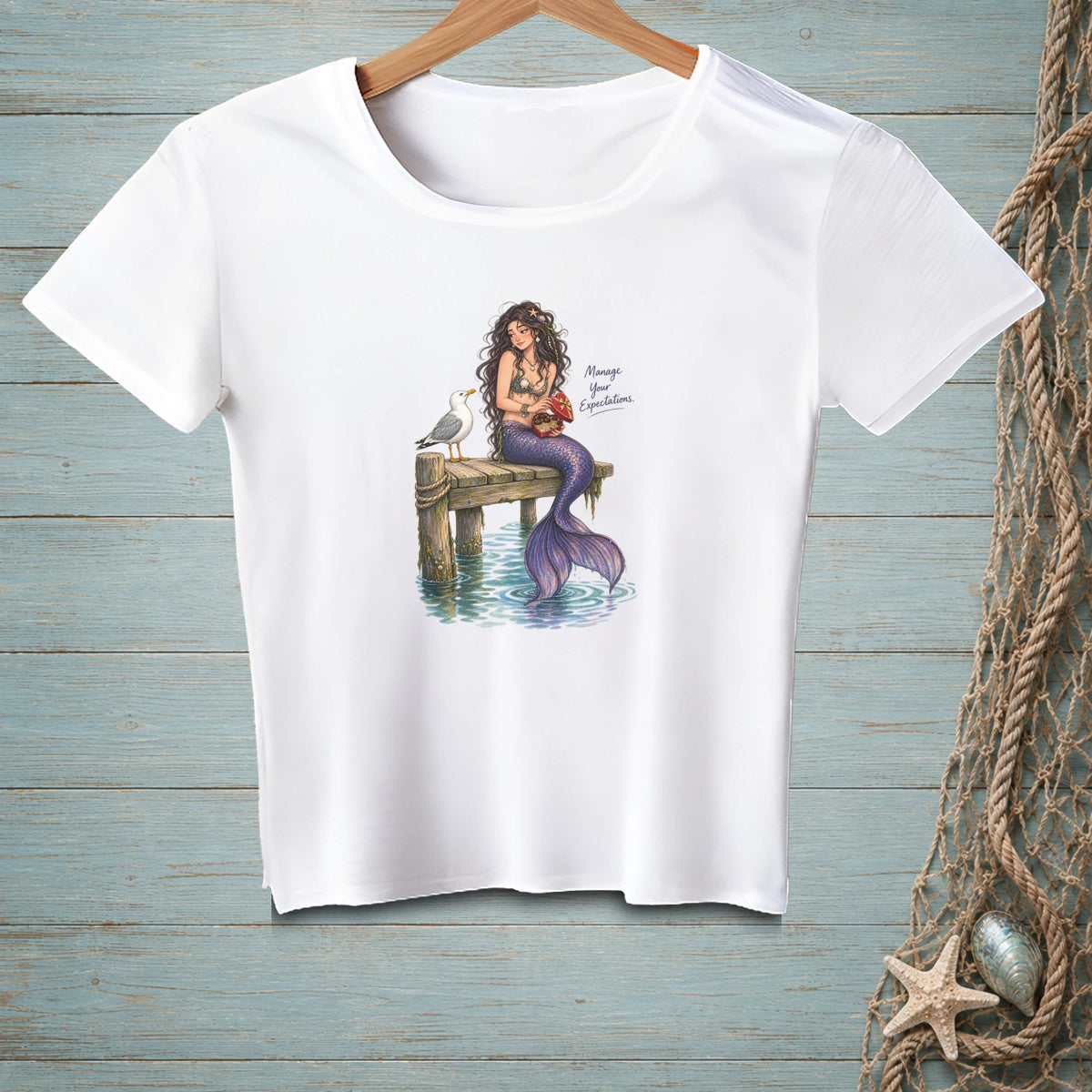 White t-shirt with a mermaid, seagull, and text "Manage Your Expectations."