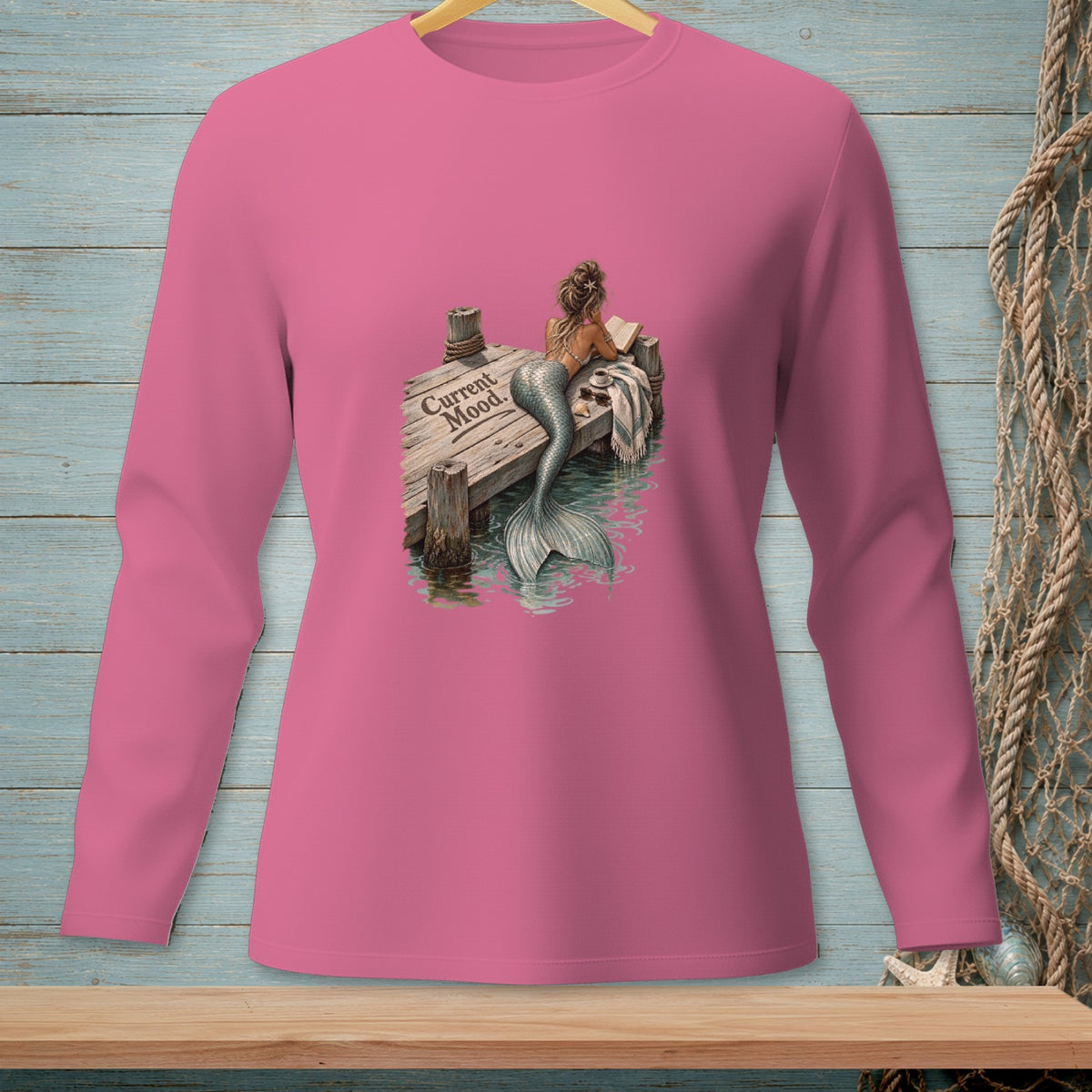 Mermaid reading on a dock with "Current Mood." text, on a pink long-sleeve shirt.