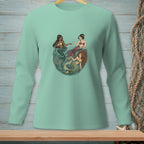 Three mermaids in a circular design on a light teal long-sleeve shirt.