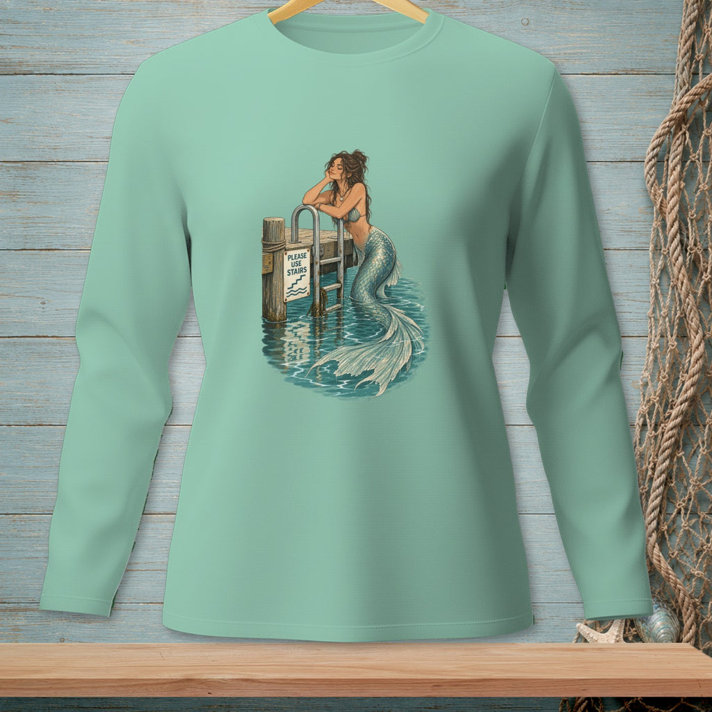 Mermaid resting on dock railing with "Please Use Stairs" sign, surrounded by water.