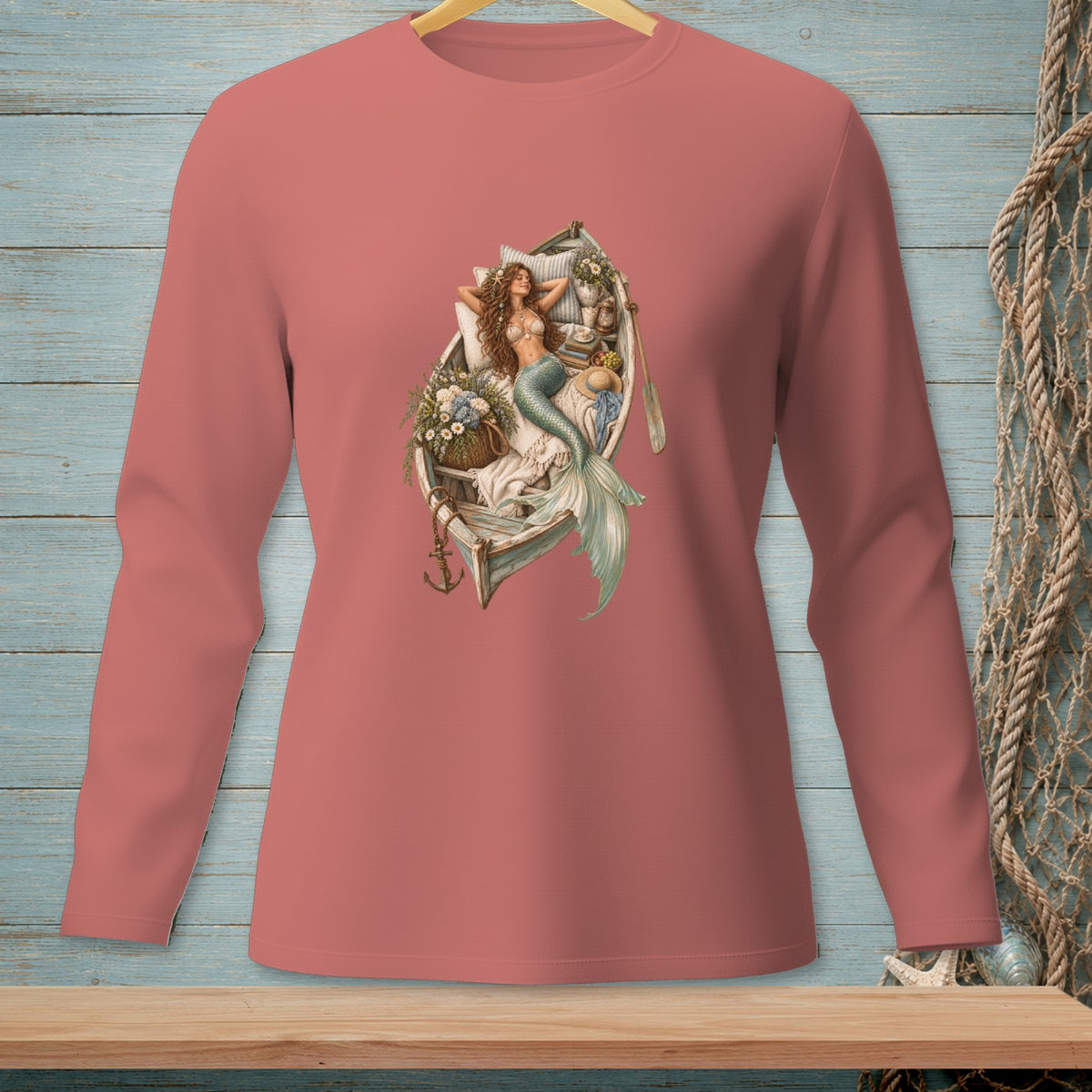 Mermaid lounging in a boat filled with flowers and books, on a long-sleeve shirt.