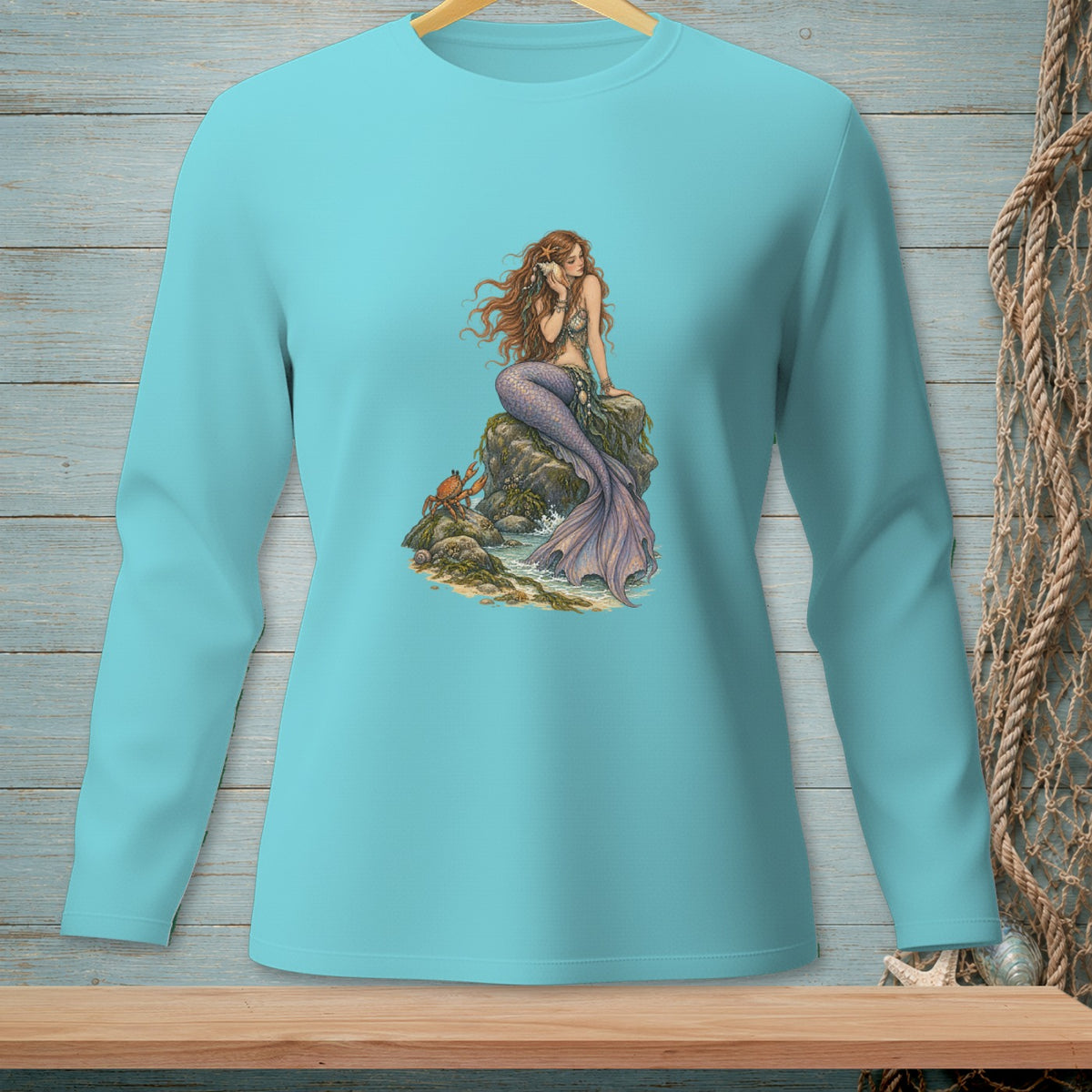 Long-sleeve aqua t-shirt with illustration of a mermaid on rocks with a crab.