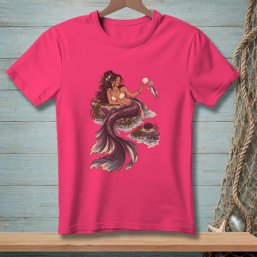 Pink t-shirt with a detailed illustration of a mermaid holding seashells and a fish.