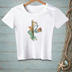 White t-shirt with two mermaids by a wooden post and a small boat.