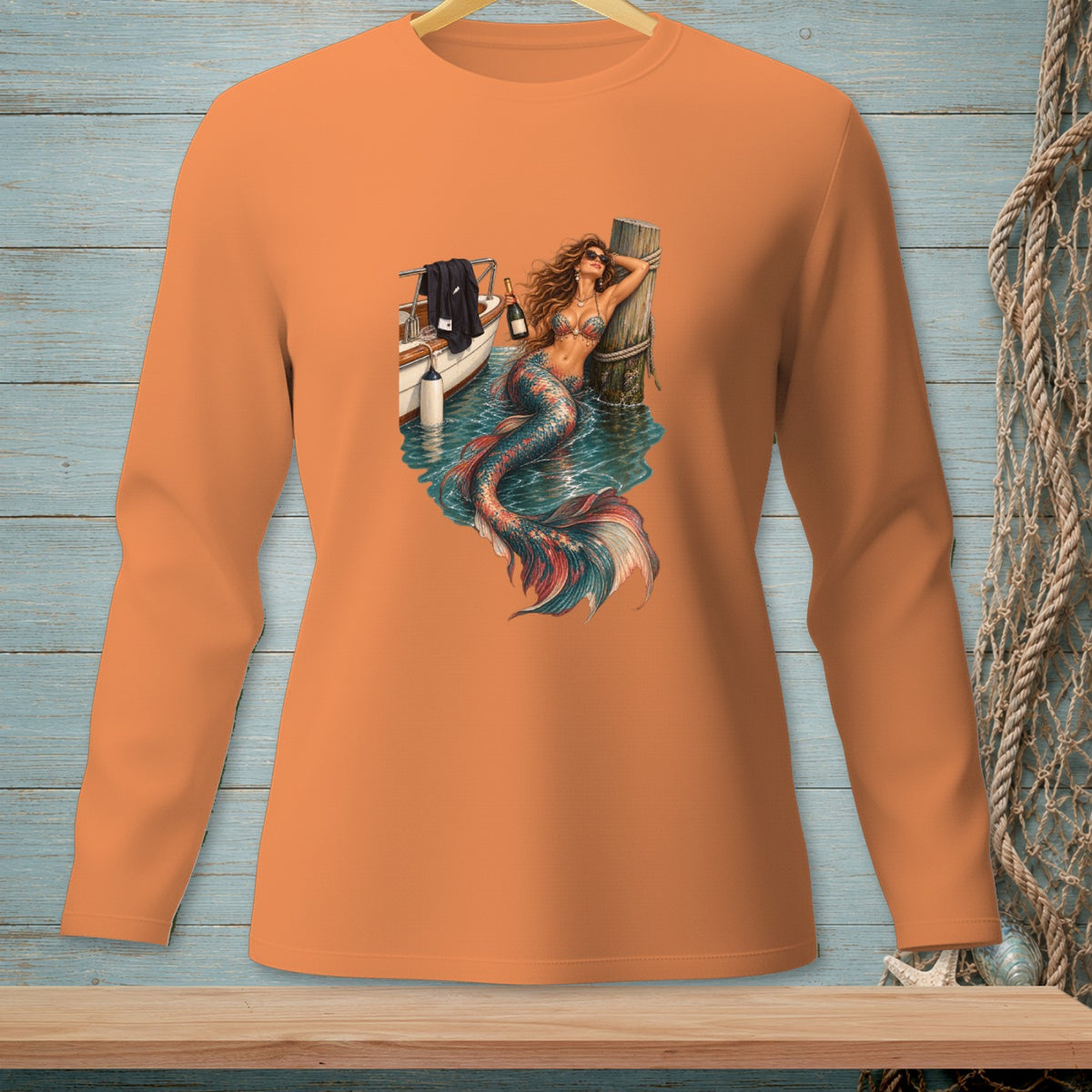Orange long sleeve shirt with a graphic of a mermaid on a boat at a dock.