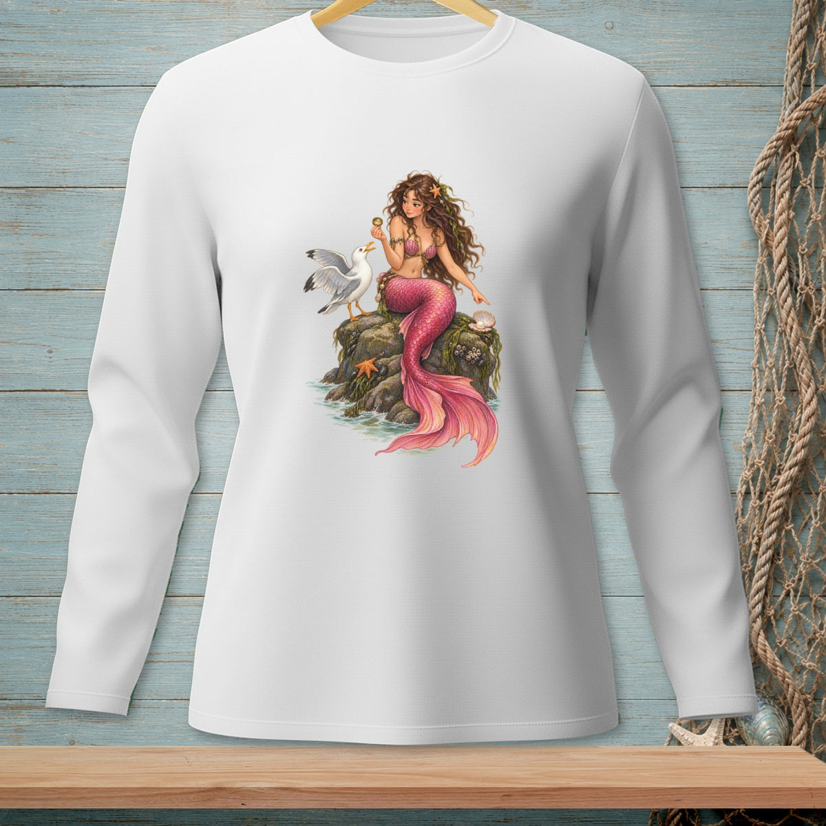 White long-sleeve shirt featuring a mermaid and seagull on a rock.