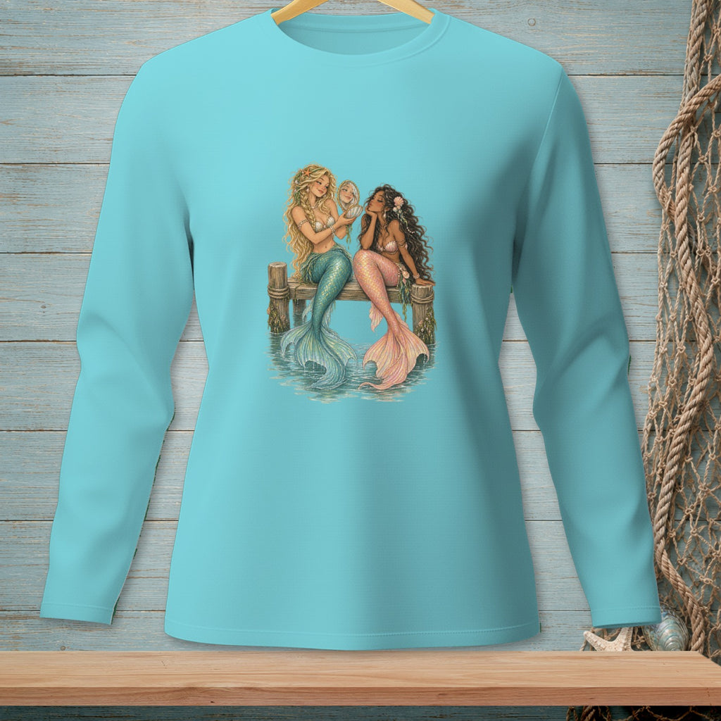 Two mermaids with colorful tails sitting on a wooden dock, one holding a mirror.