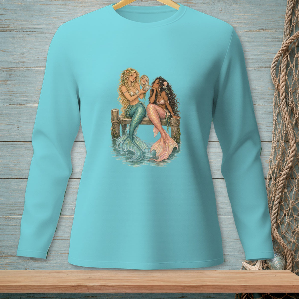 Two mermaids with colorful tails sitting on a wooden dock, one holding a mirror.