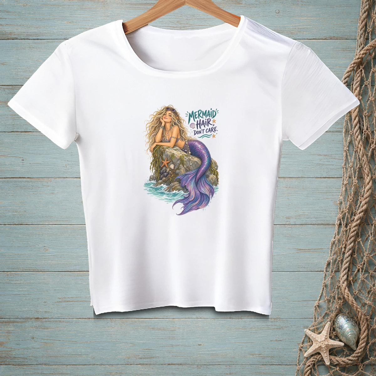 White t-shirt with a graphic of a mermaid on a rock and text "Mermaid Hair Don't Care."