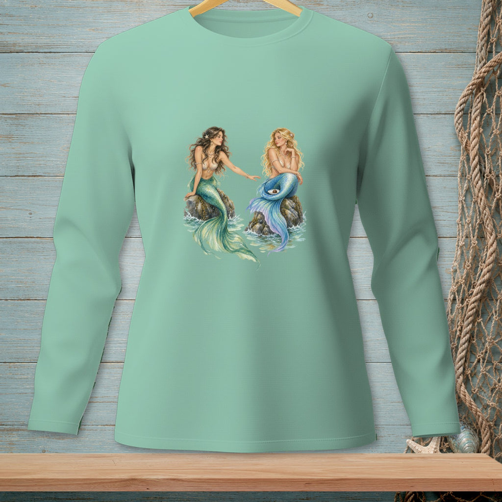 Two mermaids with colorful tails sit on rocks, surrounded by water.