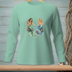 Two mermaids with colorful tails sit on rocks, surrounded by water.