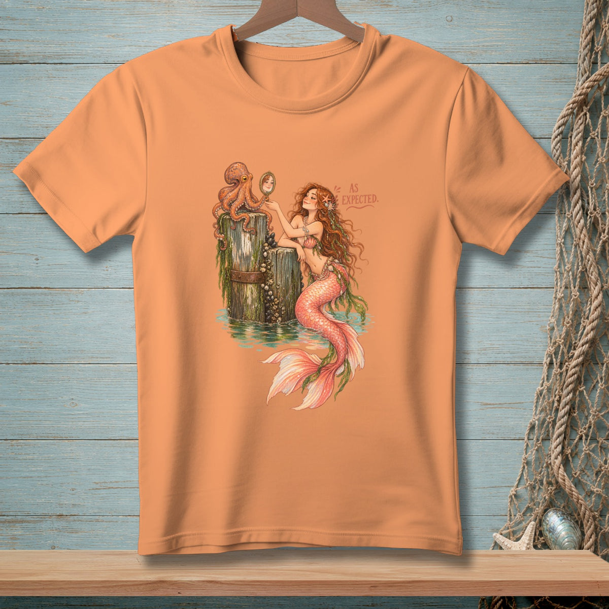 Orange t-shirt featuring a mermaid and octopus with text "AS EXPECTED".