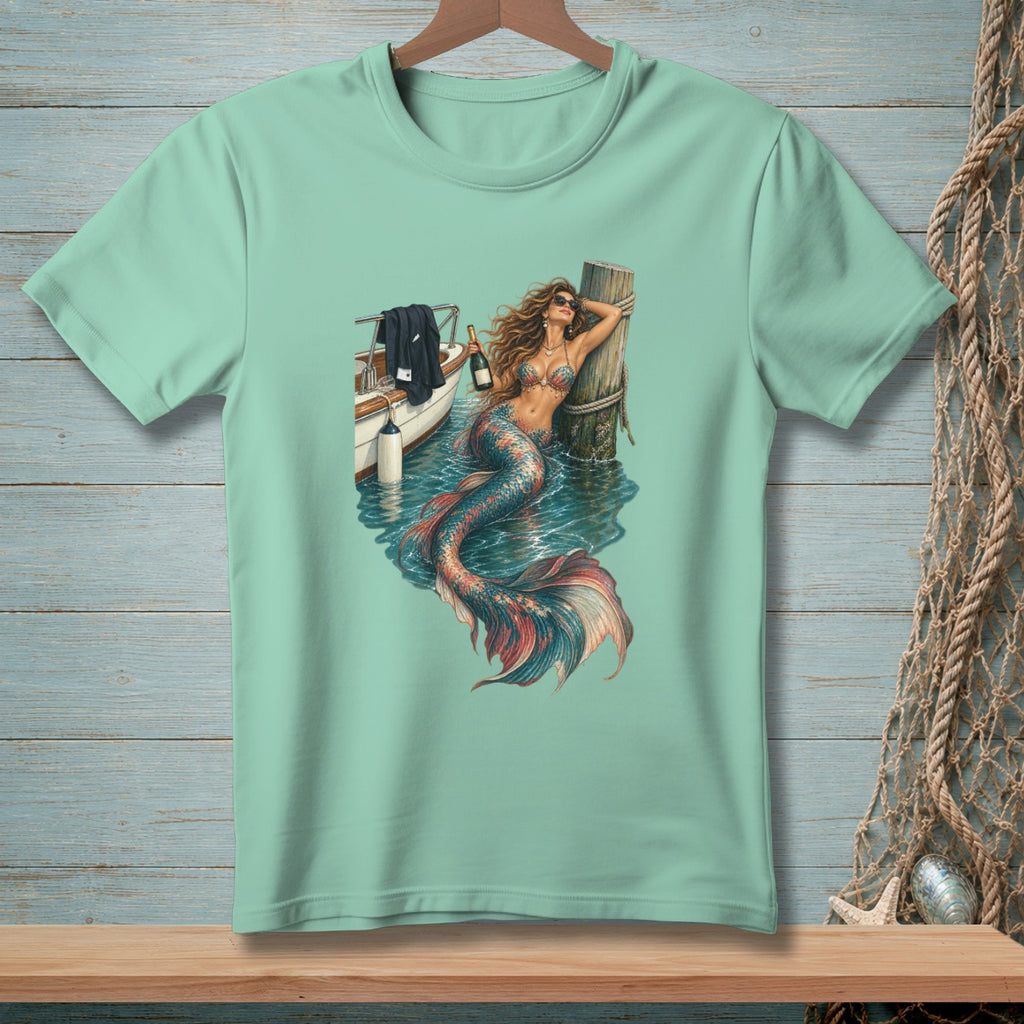 Mint t-shirt graphic featuring a mermaid lounging by a boat with a bottle of champagne.