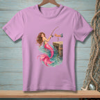 Illustration of a mermaid with pink tail fishing from a wooden pier.