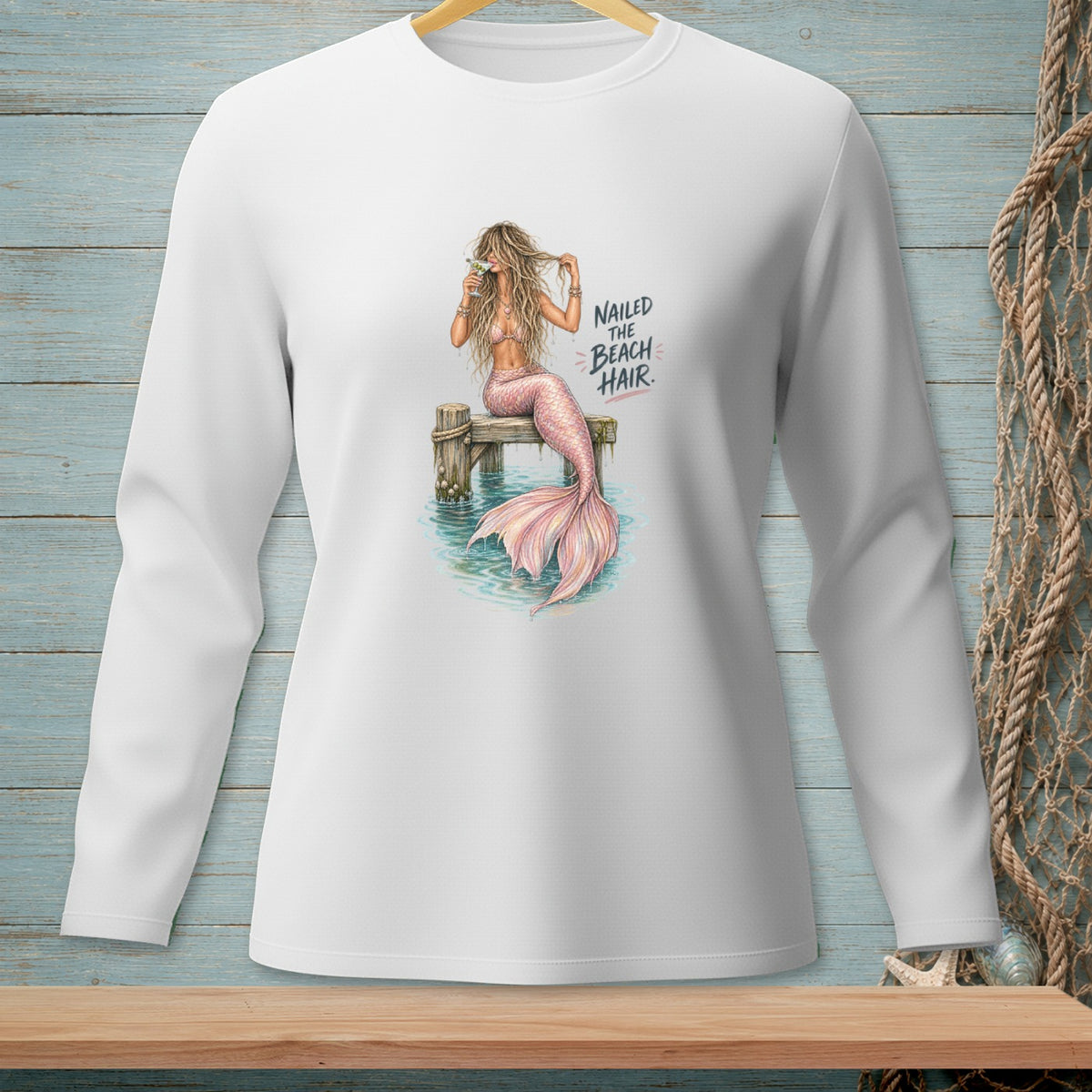 Illustration of a mermaid with pink tail on dock, holding a drink, text reads "Nailed the Beach Hair."