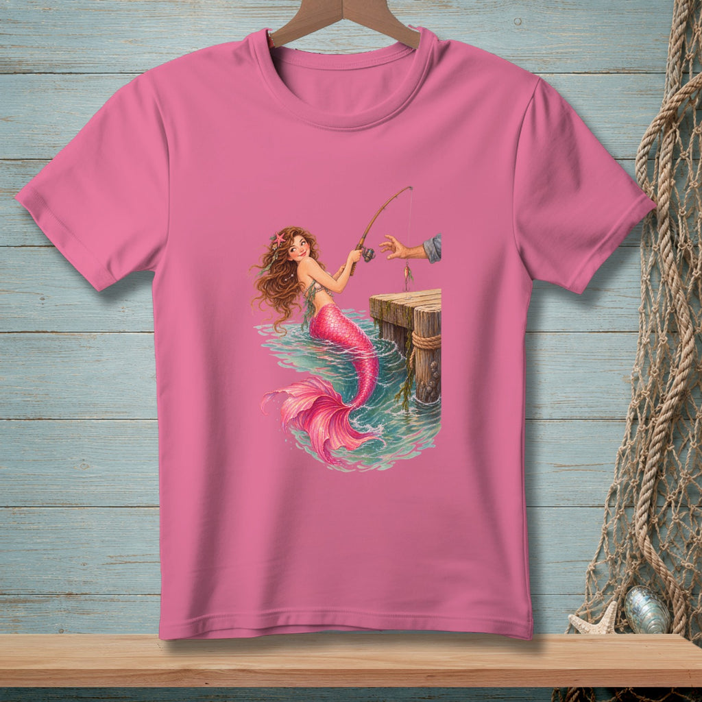 Illustration of a mermaid fishing off a wooden dock on a pink t-shirt.