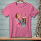 Illustration of a mermaid fishing off a wooden dock on a pink t-shirt.