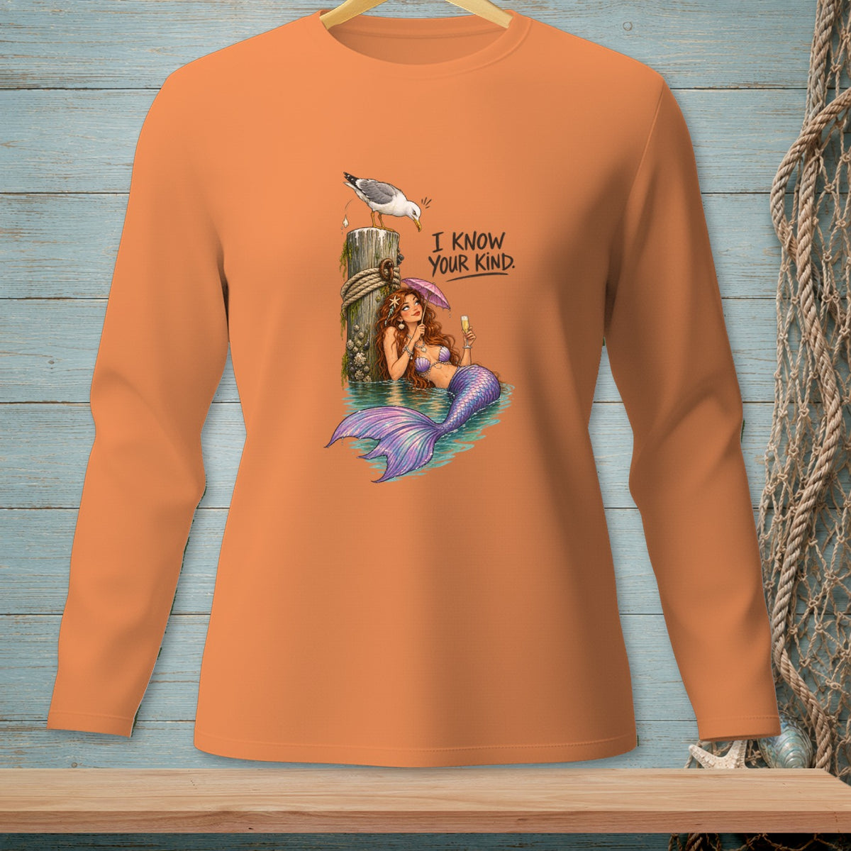 Orange long-sleeve shirt with a mermaid and seagull graphic and text.