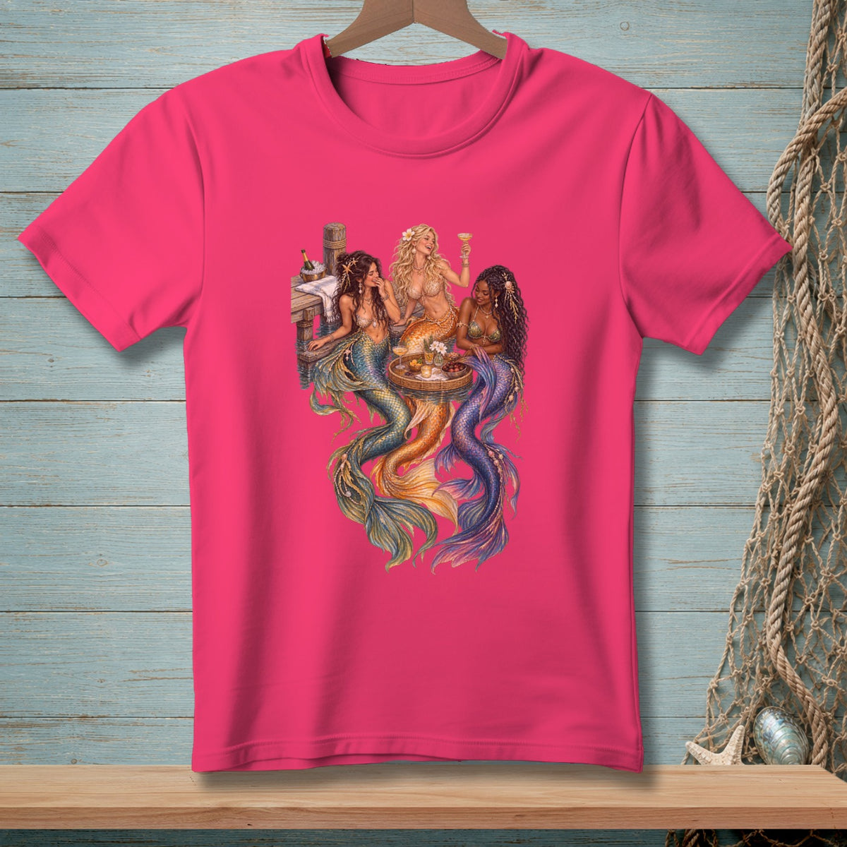 Three mermaids sit on a dock, sharing drinks and snacks.