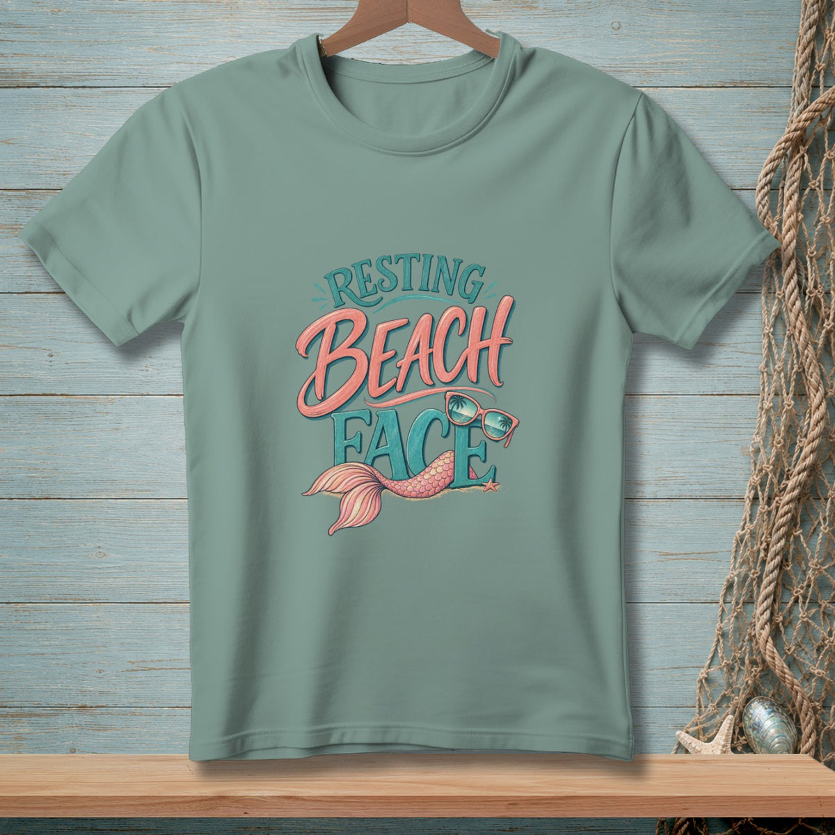 Teal t-shirt with "Resting Beach Face" text, mermaid tail, and sunglasses graphic.