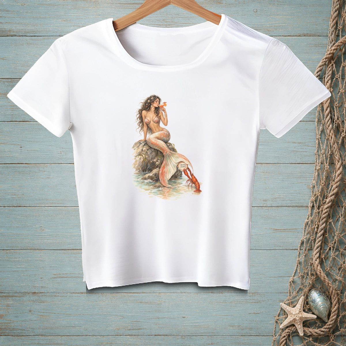 White t-shirt with watercolor art of a mermaid and lobster by the water.