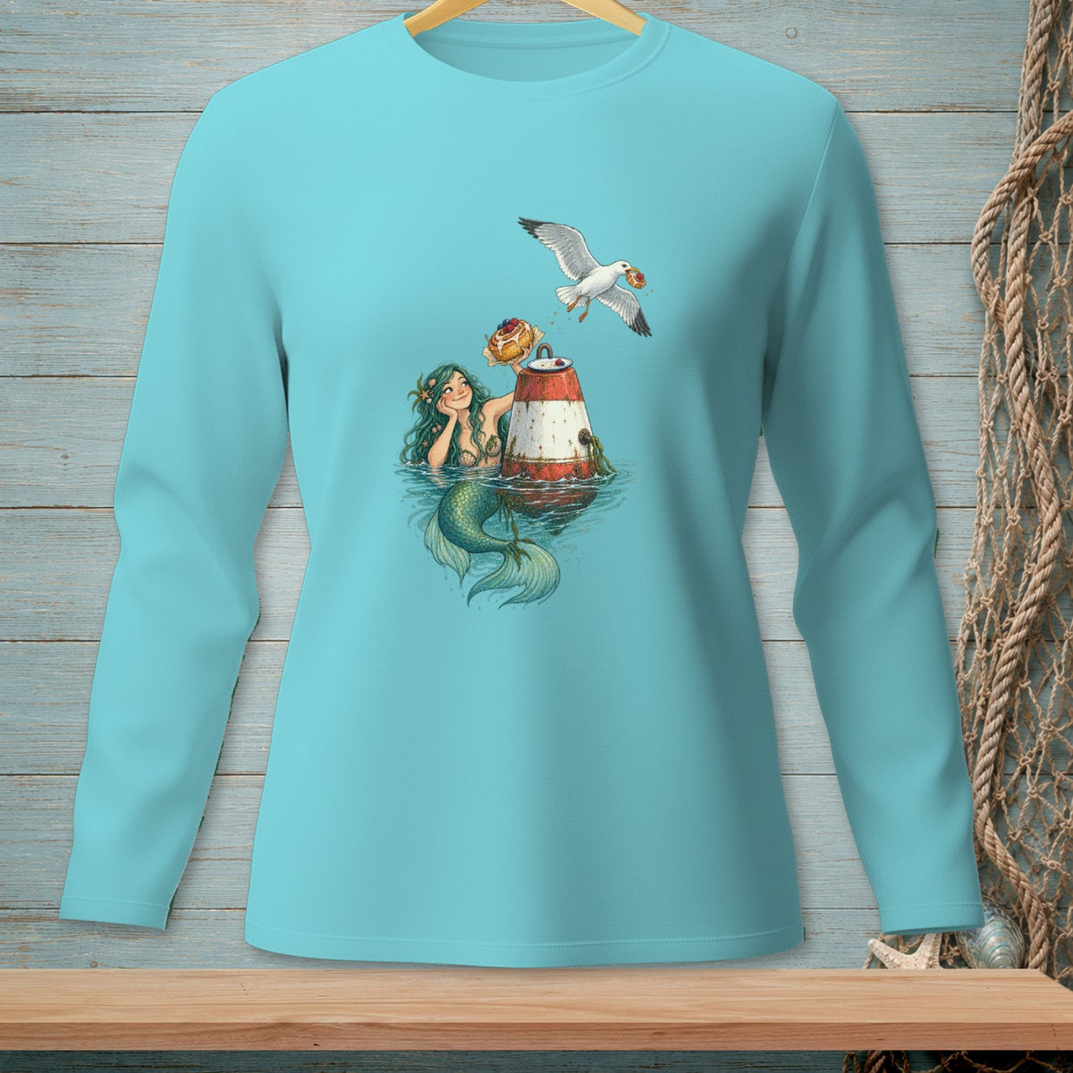 Mermaid with seagull and donuts on a buoy graphic on a teal long-sleeve shirt.