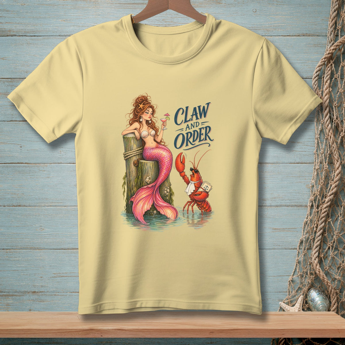 T-shirt with a mermaid and lobster on a wooden post, reads "Claw and Order."
