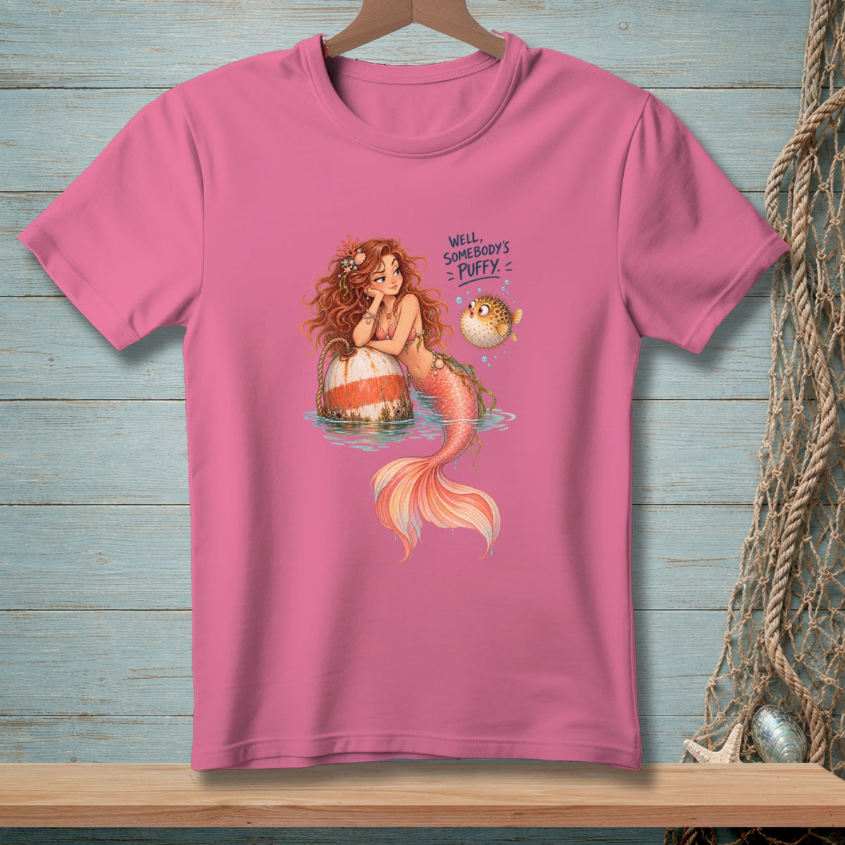 Pink t-shirt with a mermaid, pufferfish, and text that reads "Well, Somebody's Puffy."