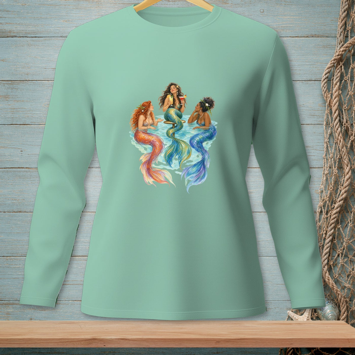 Three mermaids with colorful tails drink cocktails in stylized water.