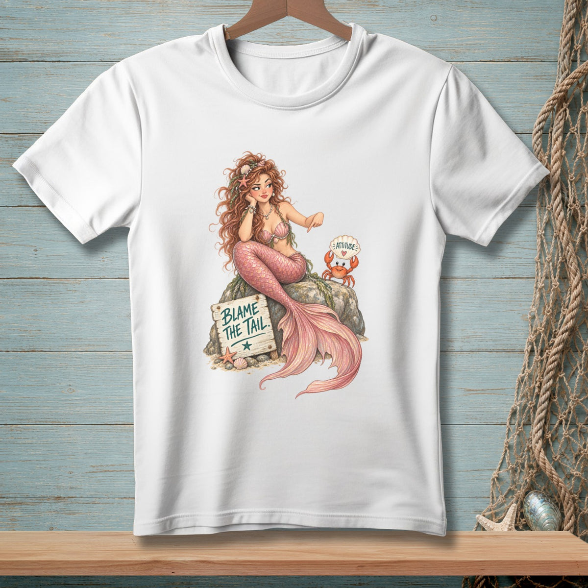 Mermaid and crab sit on a rock near a sign that reads "BLAME THE TAIL."