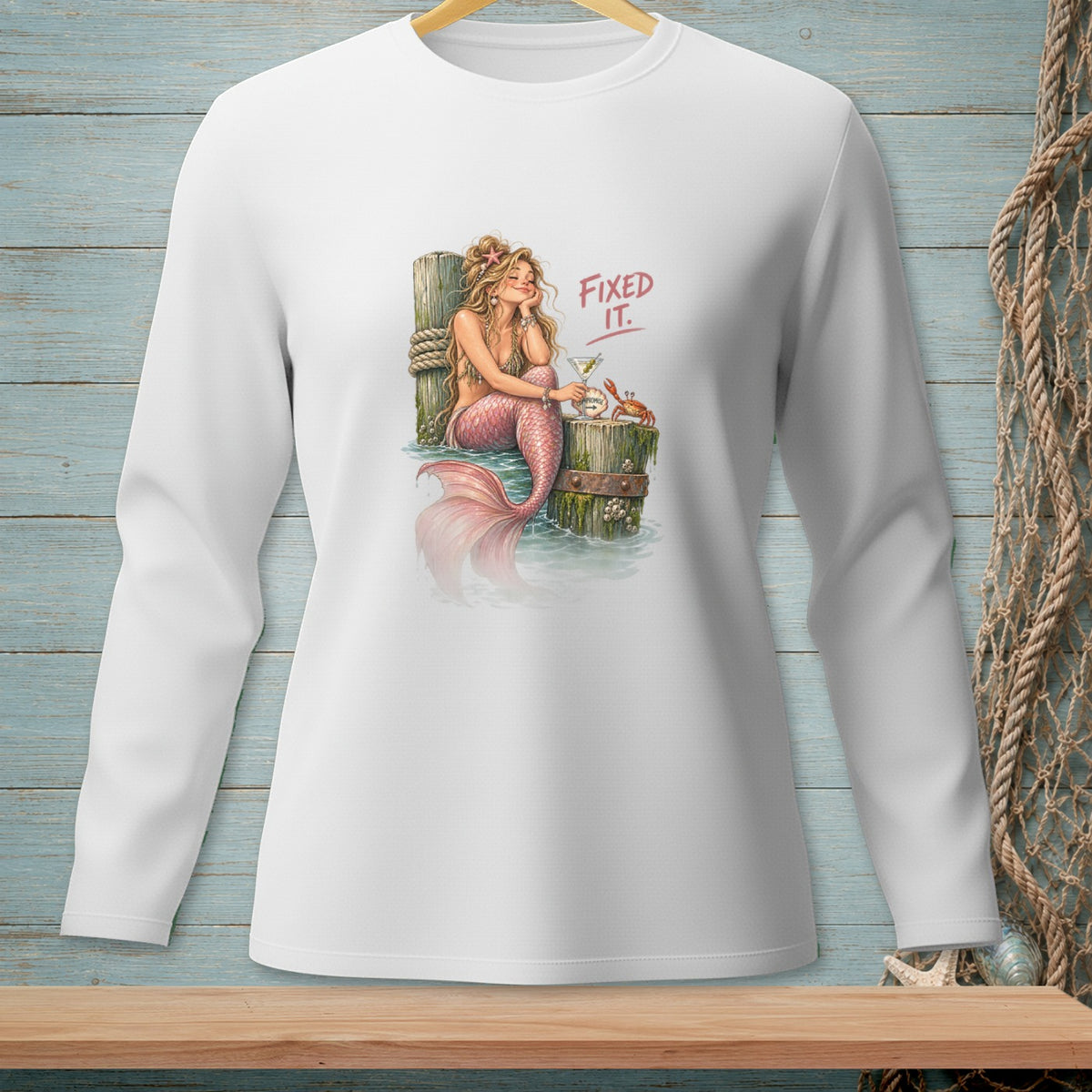 Mermaid with pink tail drinks cocktail on dock, with crab and text "FIXED IT.".