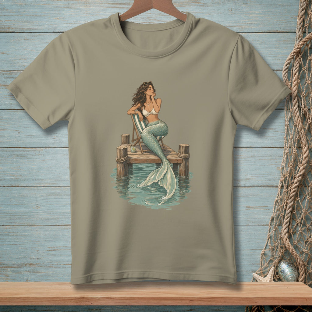 Mermaid with flowing hair sitting on a dock, with her tail in the water.