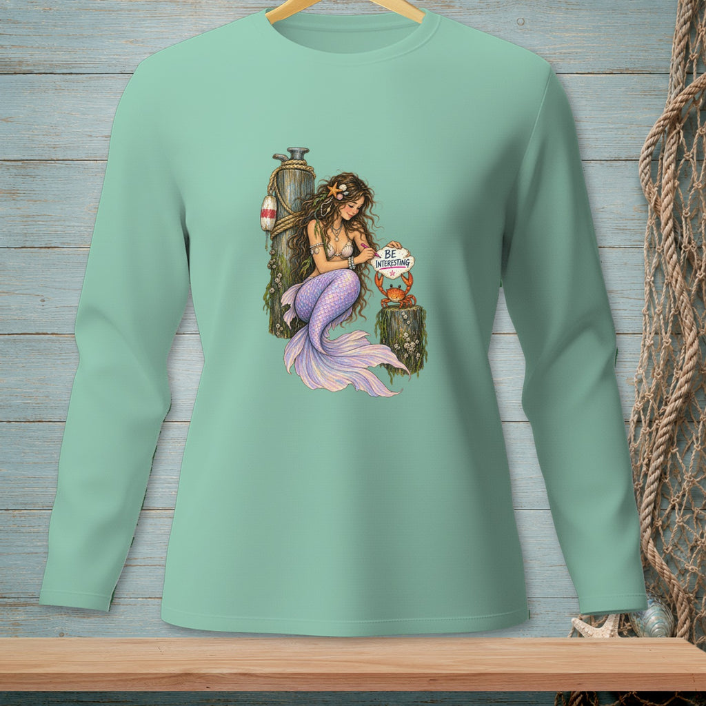 Mermaid with purple tail and crab holding sign "Be Interesting"