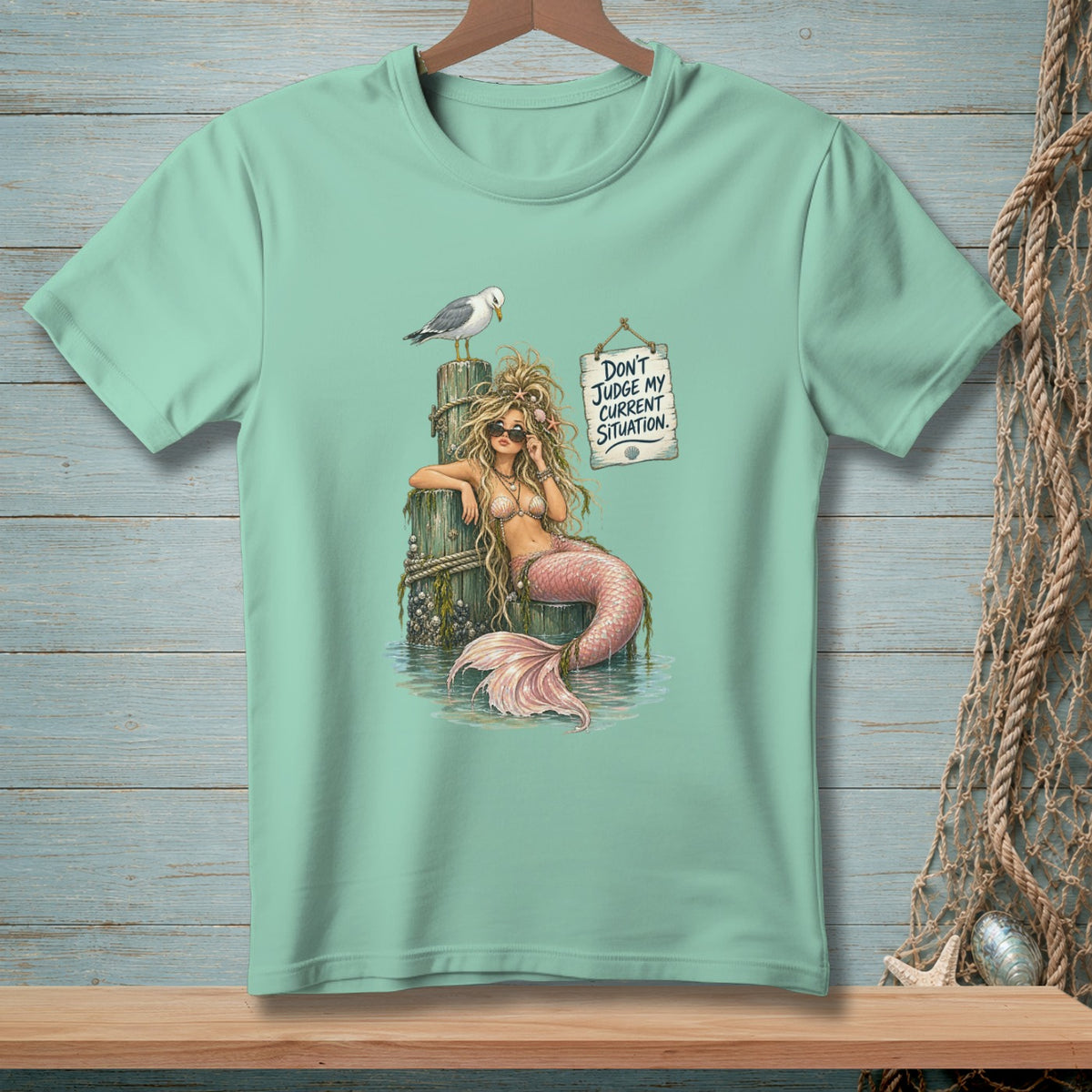 Mint t-shirt with mermaid illustration and text "DON'T JUDGE MY CURRENT SITUATION."