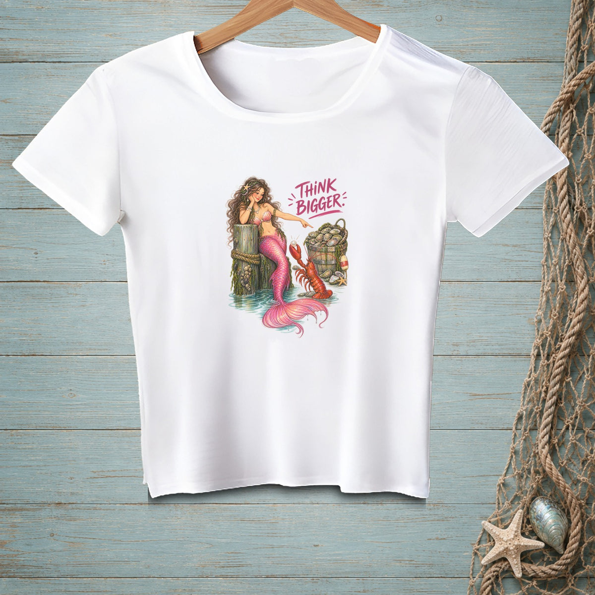 White t-shirt with a mermaid, lobster, and basket of shells graphic saying "THINK BIGGER".