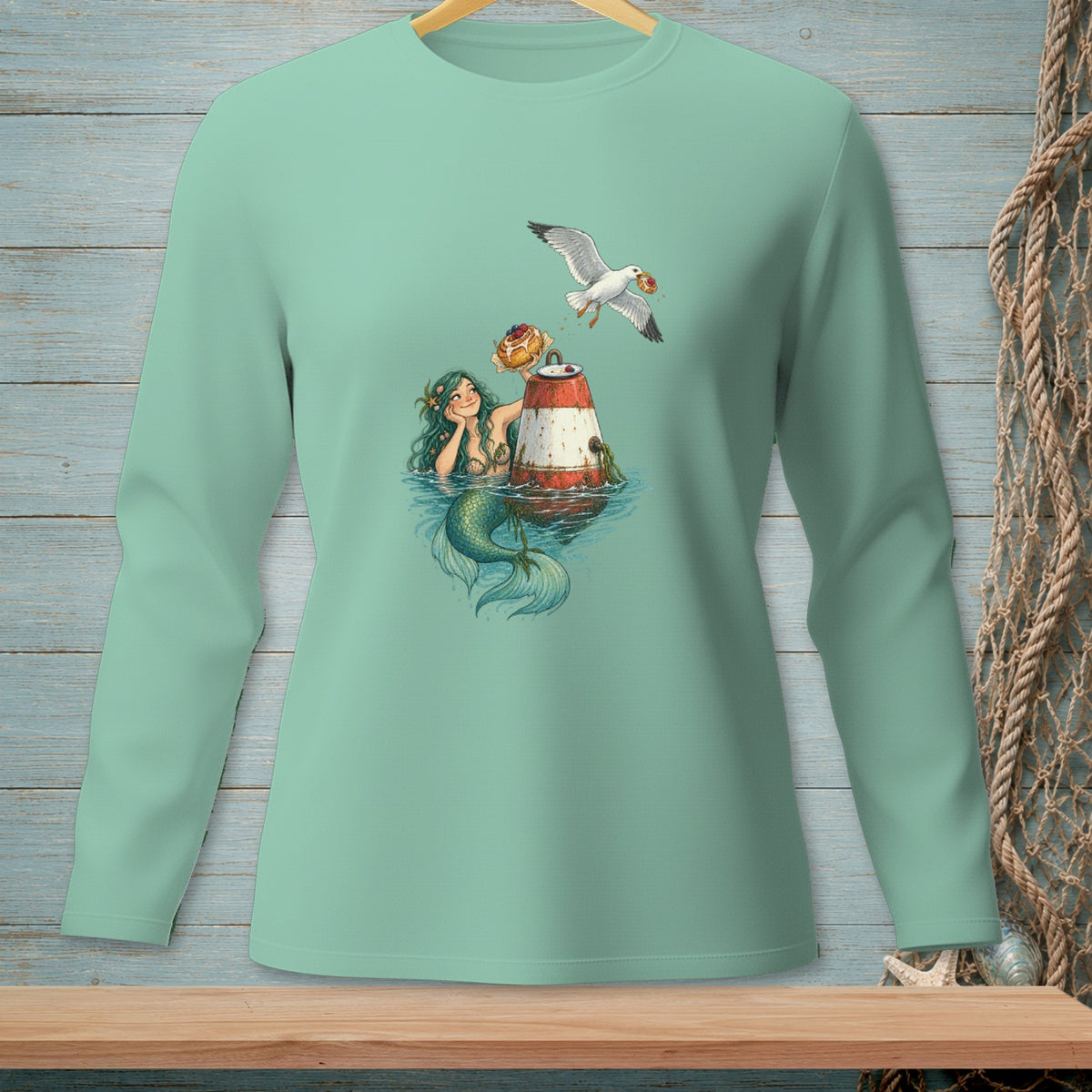 Mermaid with donut and seagull on a buoy design on a mint green long-sleeve shirt.