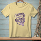 Light yellow t-shirt with "Currently Not Caring" and a mermaid tail graphic.