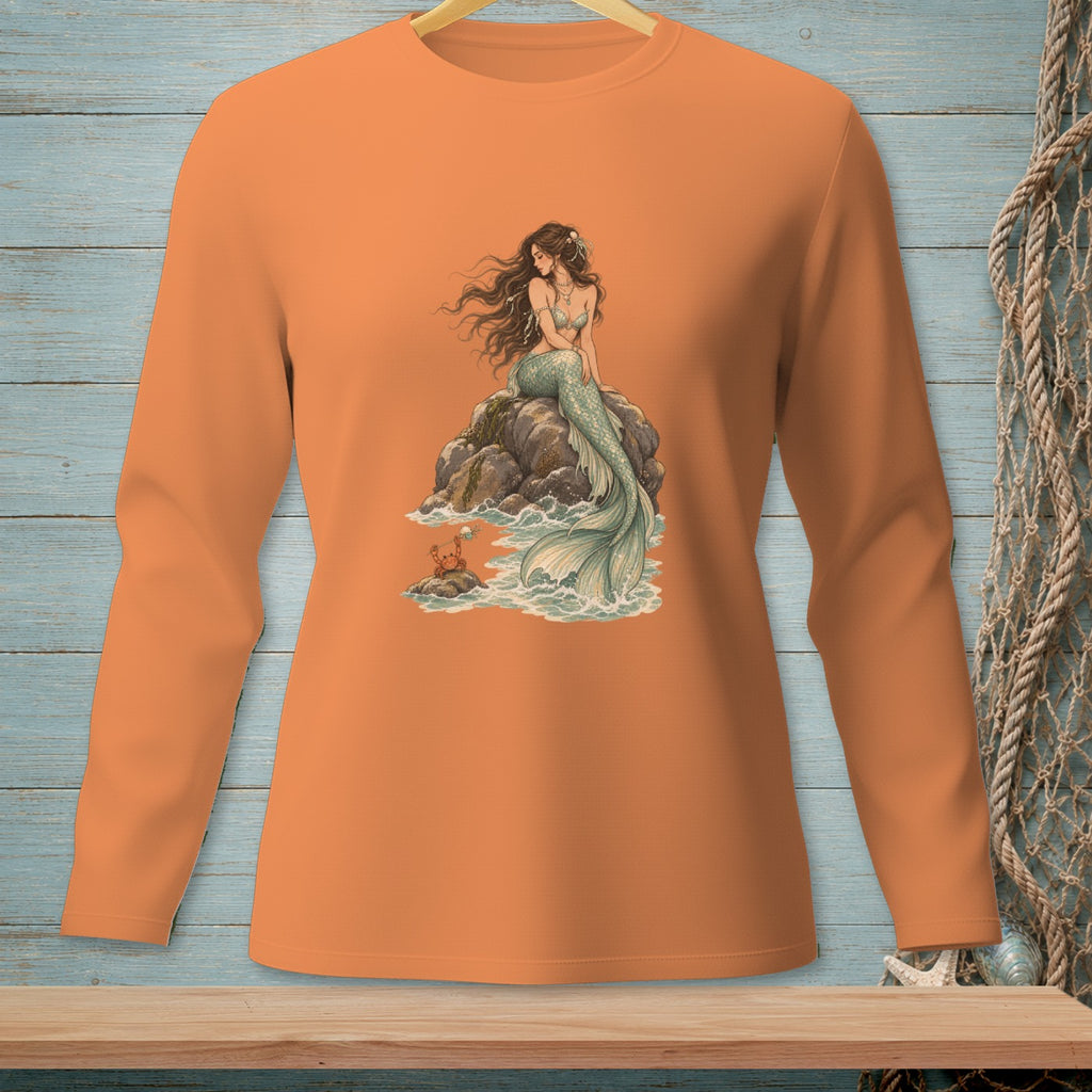Long sleeve orange shirt with a mermaid sitting on rocks by the sea.