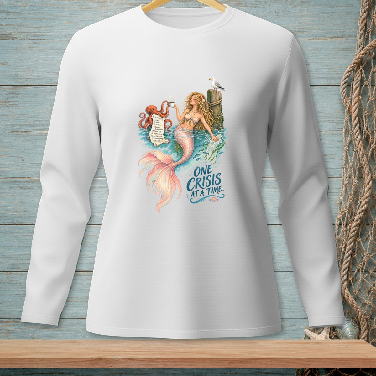 White long-sleeve shirt with a mermaid, octopus, and text "One Crisis At A Time."